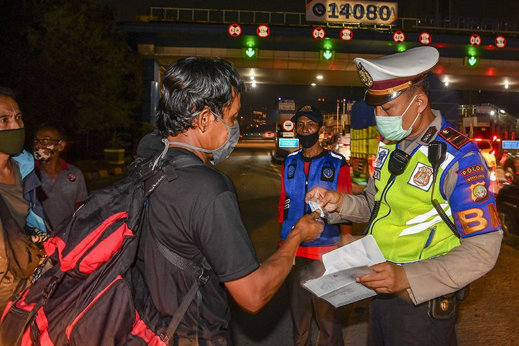 Petugas kepolisian memeriksa dokumen milik calon pemudik yang terjaring razia penyekatan di Pintu Tol Cikarang Barat, Bekasi, Jawa Barat, Kamis (21/5/2020). Calon pemudik yang terjaring razia penyekatan oleh Polda Metro Jaya tersebut dibawa ke Terminal Pulo Gebang untuk kemudian diarahkan kembali menuju Jakarta.