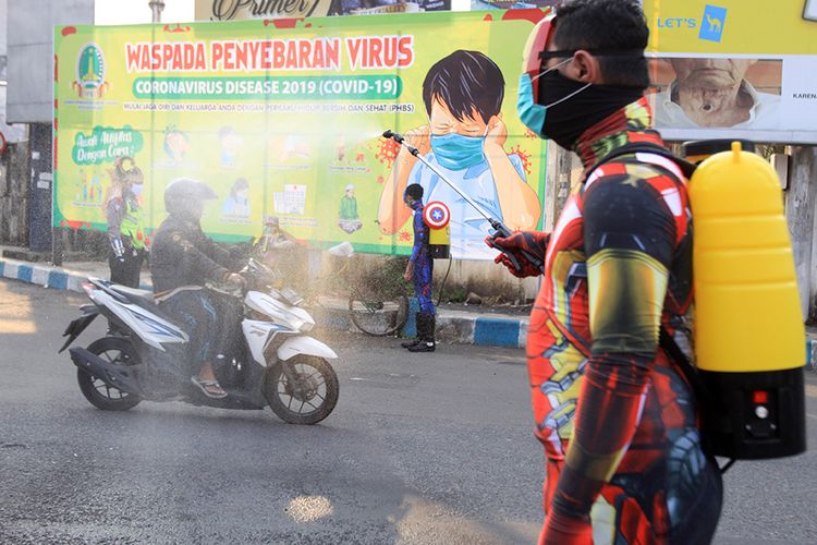 Sejumlah petugas kepolisian berpakaian superhero menyemprotkan cairan disinfektan di jalan Panglima Sudirman kawasan Kebonagung, Pasuruan, Jawa Timur, Kamis (9/4/2020). Penyemprotan cairan disinfektan tersebut bertujuan untuk mencegah penyebaran virus corona (Covid-19).