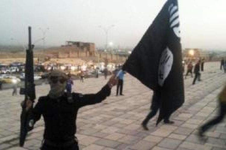 Seorang teroris ISIS memegang bendera dan senjata di Mosul, Irak.