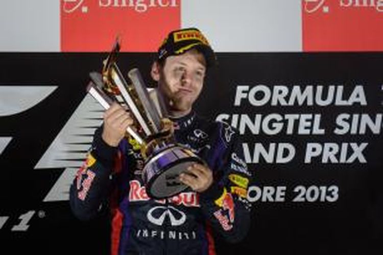 Pebalap Red Bull Racing asal Jerman, Sebastian Vettel memegang trofi juara GP Singapura, di atas podium Srikuit Marina Bay Street, Minggu (22/9/2013).