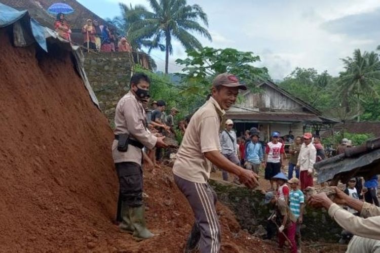 Polisi dan warga bergotong royong membantu membersihkan longsor yang menimbun rumah warga di Pekon Batu Patah, Tanggamus, Lampung.
