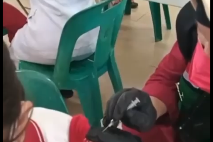 Tangkapan layar video yang merekam vaksinator di Medan diduga menyuntikkan vaksin kosong kepada anak SD di Medan.