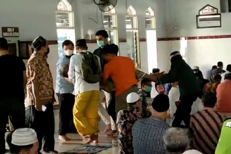 Takmir masjid dibantu beberapa jemaah menolong Karmidi keluar barisan shaf.