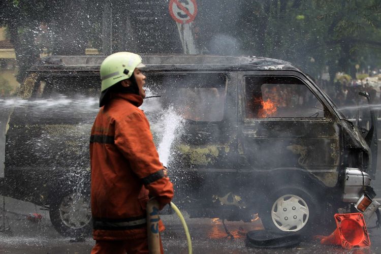 Petugas berusaha memadamkan mobil Daihatsu Zebra B2791AJ yang terbakar di Jalan Trunojoyo, samping Mabes Polri, Kebayoran Baru, Jakarta, Rabu (4/2/2015). Mobil itu membawa lima tangki berisi ratusan liter bahan bakar minyak.  KOMPAS IMAGES/KRISTIANTO PURNOMO