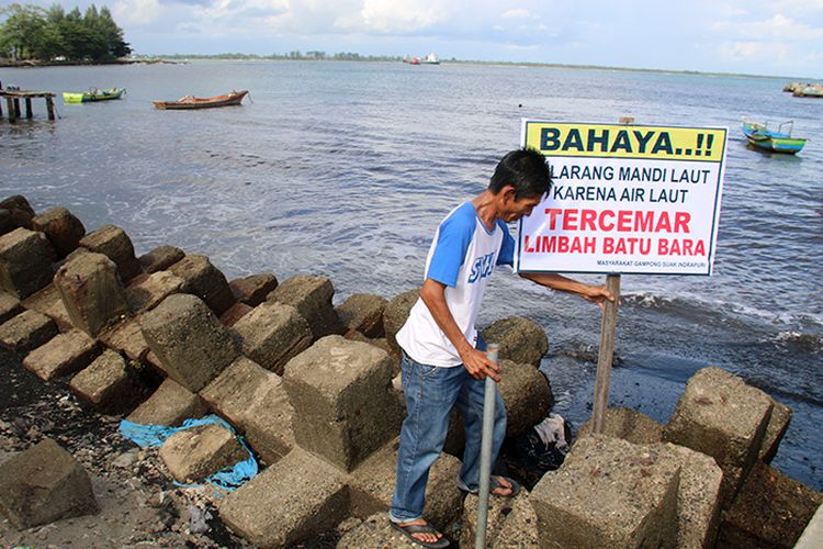 Abdul Kais (50) sekretaris Desa Suak Indrapuri, Kecamatan Johan Pahlawan , Kabupaten Aceh Barat bersama warga memasang pamplet pelarangan madi bagi penjung pantai wisata Suak Indrapuri karena telah tercemar limbah batubara, Jum,at (11/08/17). 