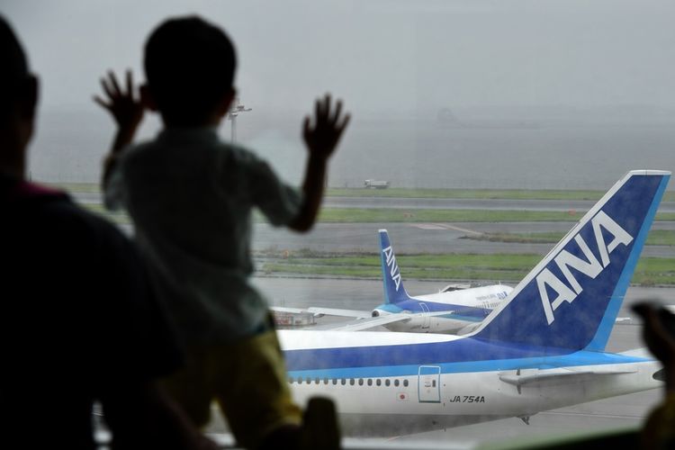 Seorang anak melihat pesawat di landasan di Bandara Haneda, Tokyo.