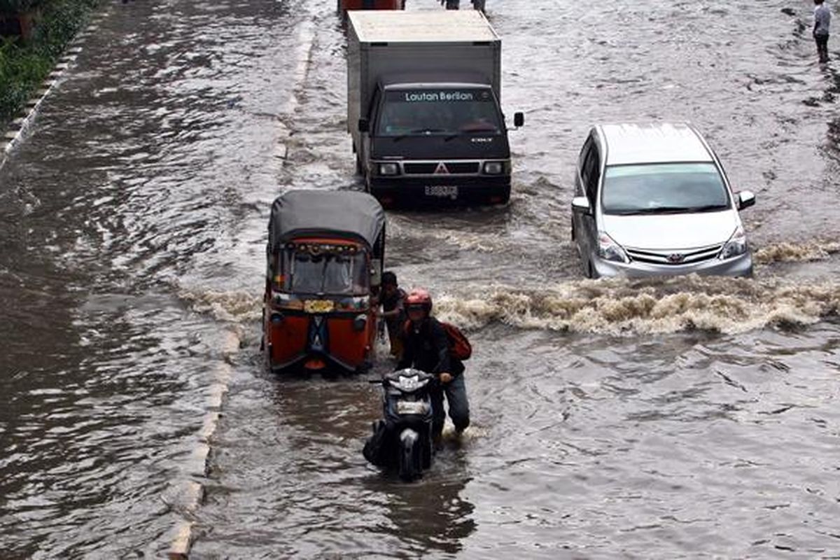 Sejumlah kendaraan melintasi banjir yang menggenangi Jalan Gunung Sahari Raya, Pademangan, Jakarta Utara, Jumat (17/1/2014). Hujan lebat yang mengguyur Jakarta sejak pagi, membuat jalan tersebut tergenang dan diperparah sistem drainase yang kurang baik. 