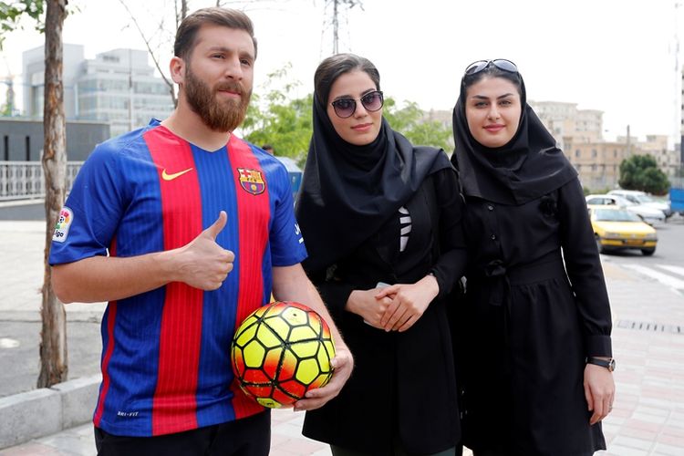 Reza Parastesh, sang kembaran Lionel Messi, sedang berpose bersama dengan dua orang gadis Iran.
