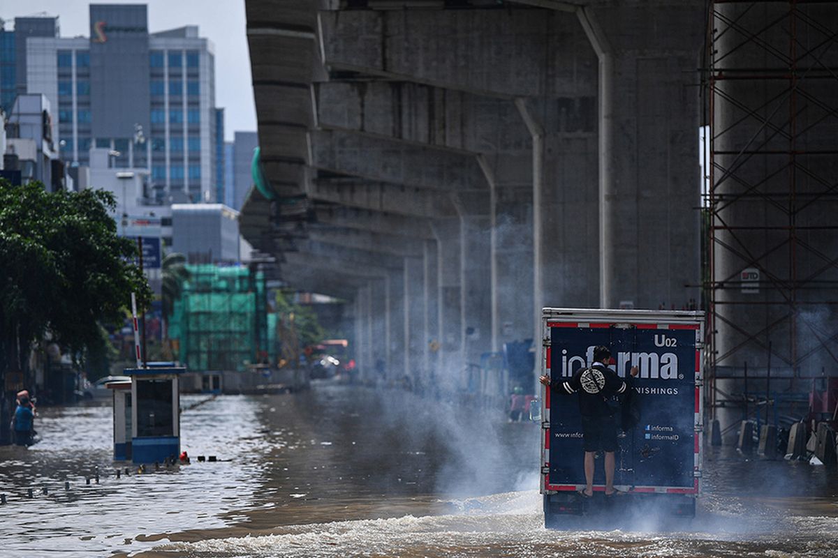 Seorang pria naik ke bagian belakang sebuah truk untuk melintasi banjir di Jalan Boulevard Barat Raya, Kelapa Gading, Jakarta Utara, Minggu (23/2/2020). Hujan deras sejak Minggu 23 Februari dini hari membuat sejumlah daerah di Ibu Kota tergenang banjir.