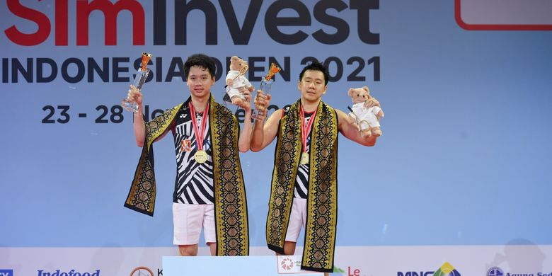 Kevin Sanjaya Sukamuljo (kiri) dan Marcus Fernaldi Gideon (kanan) saat mengangkat trofi juara Indonesia Open 2021 di Bali International Convention Centre, Minggu (28/11/2021).