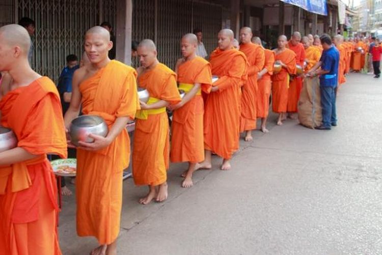 Dalam foto ini sekelompok biarawan Buddha menerima sumbangan makanan dari warga di Muang Phrae, Thailand.
