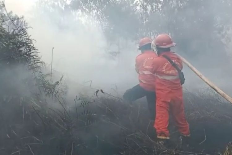 Petugas Manggala Agni diadang asap saat melakukan pemadaman karhutla di Kelurahan Pelintung, Kecamatan Medang Kampai, Kota Dumai, Riau, Senin (24/4/2023).