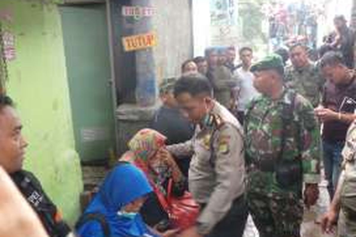 Kepala Polsek Penjaringan, Ajun Komisaris Besar Rudi berbicara menenangkan Atun (berkerudung corak merah). Atun menjerit karena backhoe tiba-tiba berada di belakang rumah. Senin (29/2/2016)