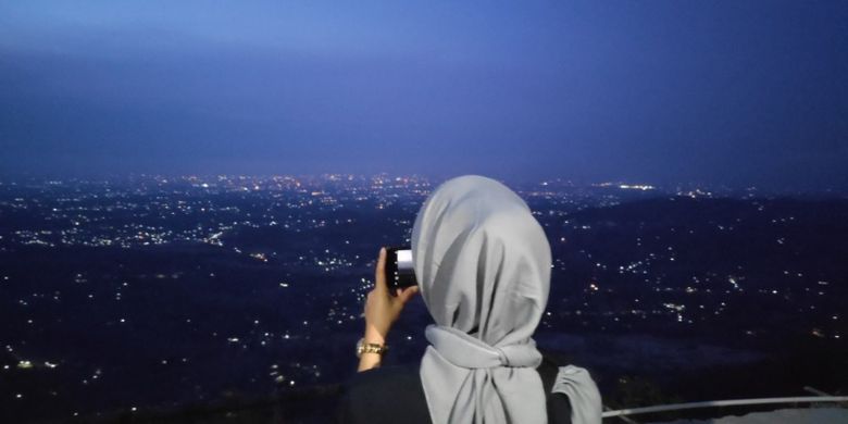Wisatawan mengabadikan kerlip lampu Yogyakarta dari Puncak Becici.