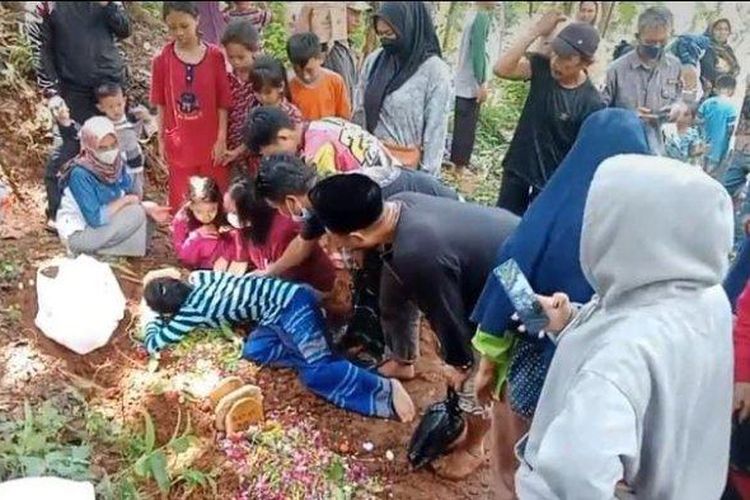 Mela Andriani (27) saat mencium nisan kedua anaknya di TPU Sukatani, Desa Ciherang, Kecamatan Sumedang Selatan, Jumat (5/5/2023).