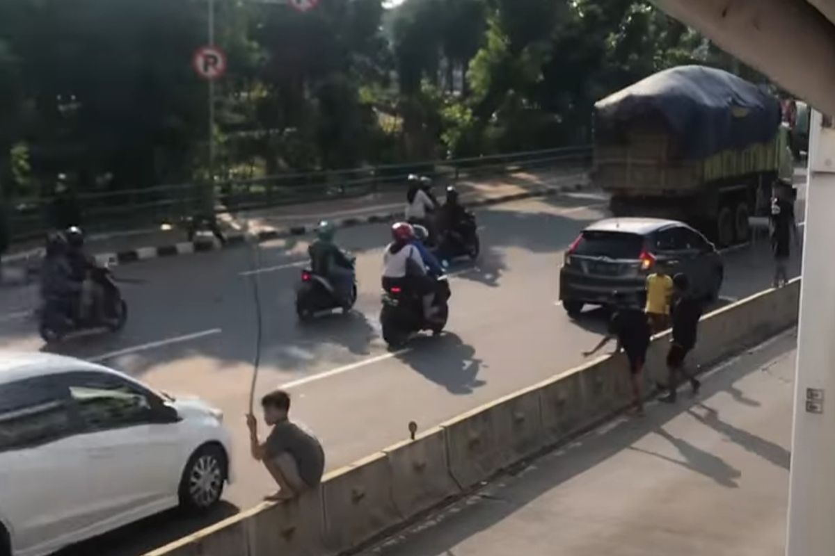 Tangkapan layar video memperlihatkan anak-anak yang berada di jalur Trans Jakarta sembari membawa ranting pohon di Jembatan Besi, Tambora, Minggu (31/7/2022).