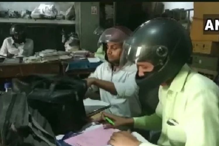 Dalam gambar yang beredar di media sosial, para karyawan kantor pemerintahan di Uttar Pradesh, India, menjadi perhatian setelah mengenakan helm di kantor.