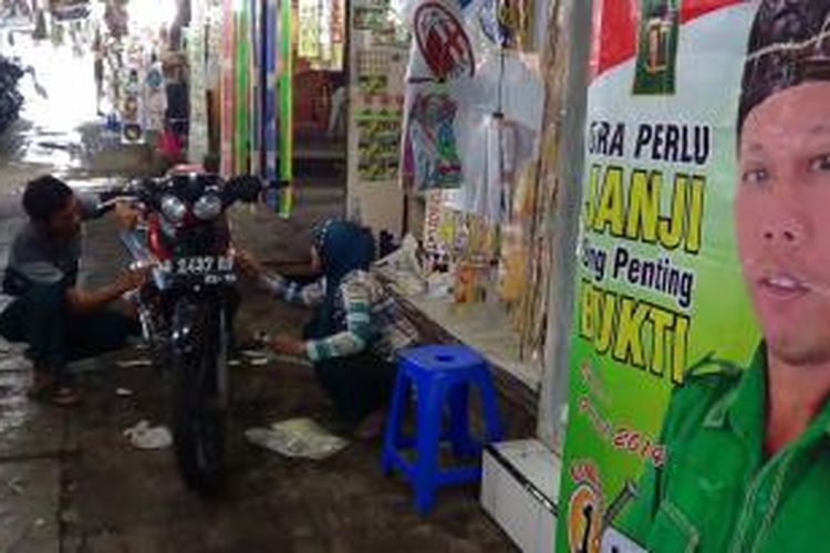 Mochamad Faisol dan istrinya Eli Rosinta menempelkan sticker motor di salah satu motor pembelinya di kawasan pasar malam di sekitaran Stasiun Tegal, Jawa Tengah, Rabu (5/1/2014). 