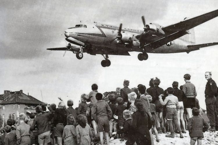 Warga Berlin menyaksikan sebuah pesawat angkut Douglas C-54 Skymaster yang membawa bantuan hendak mendarat di bandara Tempelhoff pada 1948.
