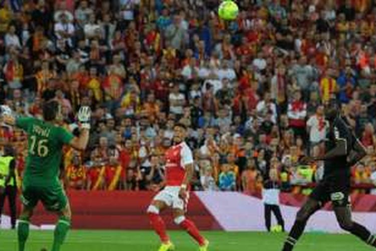 Pemain Arsenal, Alex-Oxlade Chamberlain (tengah), mencetak gol dengan mencungkil bola melewati kiper Lens, Nicolas Douchez, pada laga persahabatan di Stade Bollaert-Delelis, Jumat (22/7/2016) waktu setempat.