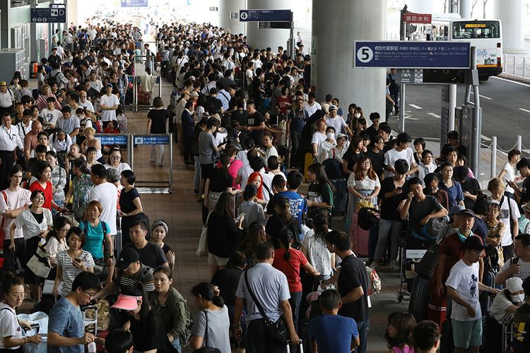 Sejumlah penumpang yang tertahan di Bandara Internasional Kansai mengantre bus yang akan mengalihkan mereka ke bandara di Kota Izumisano, Prefektur Osaka, Rabu (5/9/2018). Topan Jebi yang disebut sebagai topan terkuat dalam 25 tahun di Jepang menghantam pesisir negara tersebut pada Selasa, 4 September tengah hari, membawa angin dengan kecepatan maksimal 216 km/jam disertai hujan lebat.