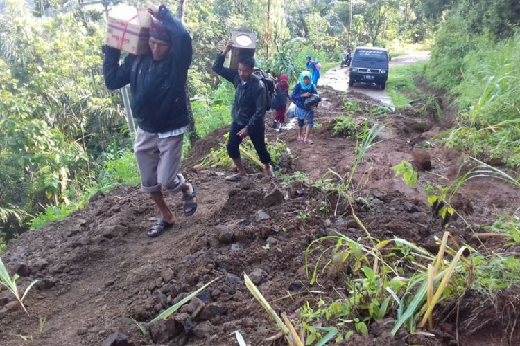Warga Desa Cimanintin harus berjalan kaki untuk keluar dari wilayah desa mereka akibat badan jalan tertutup material longsor di Jatinunggal, Sumedang, Jawa Barat, Minggu (10/2/2019). Dok. KODIM 0610/Sumedang