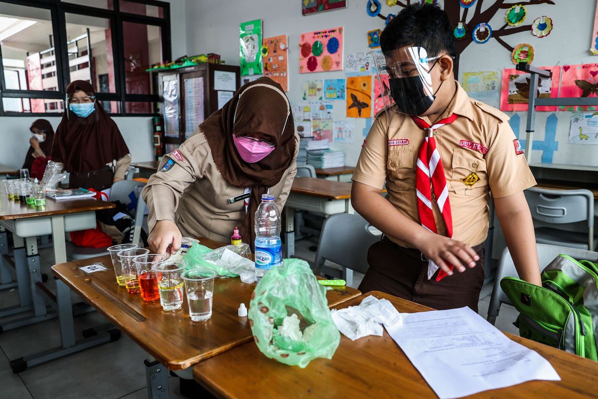 Guru memberikan materi pelajaran kepada murid saat uji coba pembelajaran tatap muka pada hari pertama di SDN 03 Palmerah, Jakarta Barat, Rabu (7/4/2021). Pemprov DKI Jakarta melakukan uji coba pembelajaran tatap muka terbatas di 85 sekolah dari jenjang SD hingga SMA mulai 7 April hingga 29 April 2021 dengan kapasitas dalam ruangan maksimum 50 persen dan penerapan protokol kesehatan yang ketat.