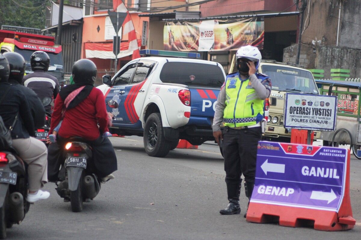 Seorang anggota polisi sedang mengatur kendaraan di bundaran Tugu Lampu Gentur Cianjur, Jawa Barat, Jumat (3/9/2021) saat pemberlakuan sistem ganjil genap di kawasan Puncak Cianjur.