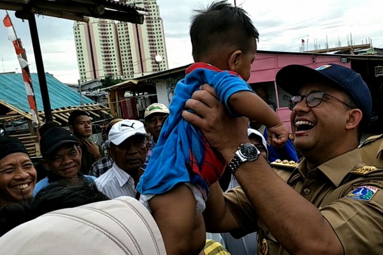 Gubernur DKI Jakarta, Anies Baswedan saat menggendong bayi bernama Muhammad Asa di Kampung Akuarium, Jakarta Utara, Senin (27/11/2017).