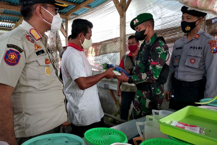 Petugas gabungan pelaksana operasi yustisi memberikan bantuan paket sembako kepada pedagang makanan di Kecamatan Binangun, Kabupaten Blitar, Jumat (16/7/2021)