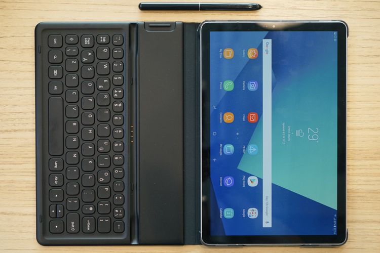 Galaxy Tab S4 dan keyboard dalam keadaan dibentangkan. Di samping mereka ada stylus S Pen yang digunakan untuk menulis, menggambar, dan melakukan aneka hal lain di permukaan layar.