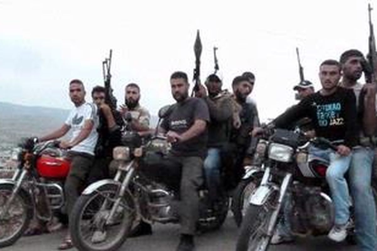 Para anggota Tentara Pembebasan Suriah mengendarai motor di pinggiran kota Homs pada 28 Juni 2012. Puluhan tentara aktif, termasuk seorang jenderal dan sejumlah perwira senior, dilaporkan menyeberang ke Turki untuk bergabung dengan pasukan oposisi.