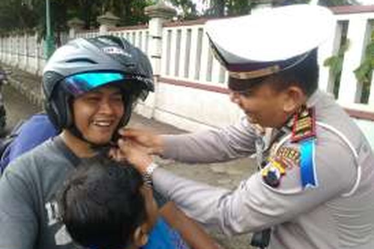 Kasatlantas Polres Brebes AKP Arfan Zulkan Sipayung memasang helm ke pengendara motor saat Ops Zebra 2016 di Jalan Jenderal Sudirman, Brebes, Jawa Tengah.