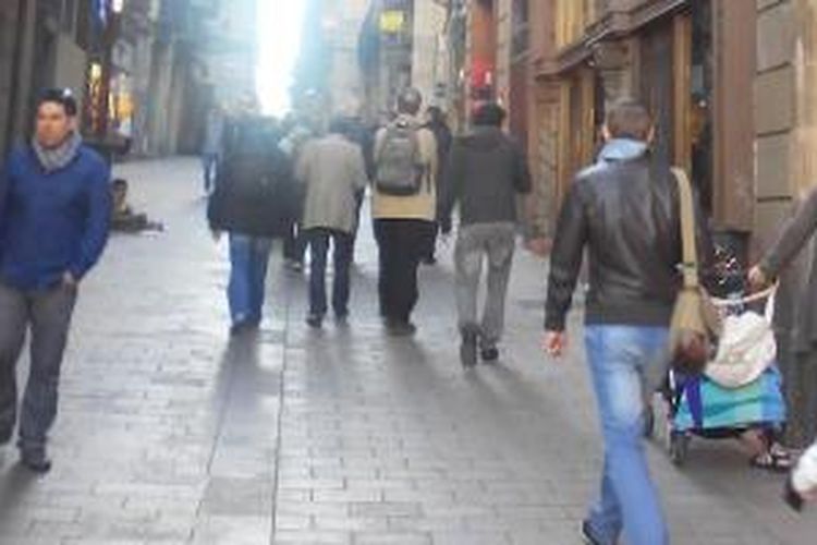 Para pengunjung dan warga berjalan kaki di kota tua Barcelona. 