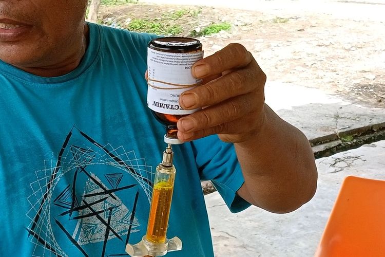 Taufik Hidayat Daulay mengisi alat suntik dengan vitamin dan obat untuk menyembuhkan sapinya yang terjangkit PMK. Obat, vitamin dan alat-alat ini dibelinya sendiri hingga menghabiskan lebih dari Rp 15 juta.