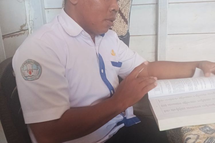Guru muatan lokal di SMP Negeri 4 Kapuas Tengah, Gino, menunjukkan buku yang digunakannya sebagai bahan ajar pada Selasa (30/9/2025)