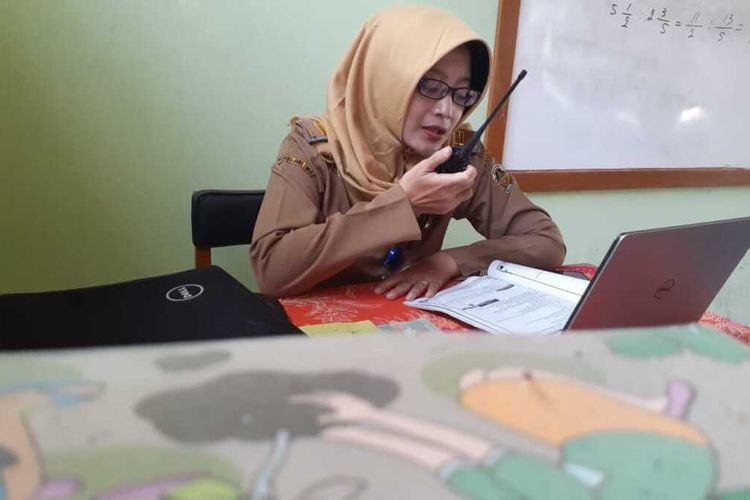 GUNAKAN HT—Nampak guru SDN 1 Balerejo, Kecamatan Kebonsari, Anifatul Maghfirullah menggunakan sarana HT untuk memberikan pelajaran dan tugas bagi siswa-siswi yang tak mampu membeli kuota internet.