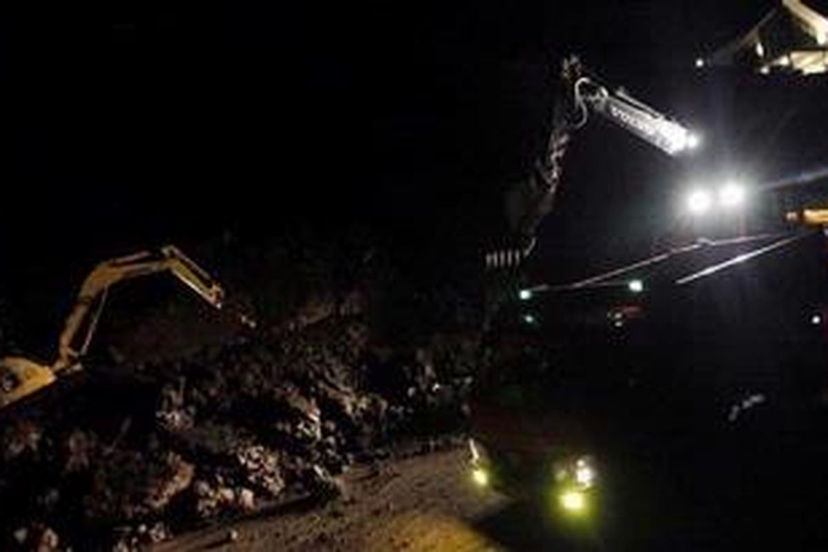 Alat berat berusaha membersihkan material longsor yang terjadi di Jalan Muhamad Yamin, Puncak, Cianjur, Jawa Barat, Kamis (10/1/2013). Akibat longsor ini jalur Puncak Pass tertutup karena tidak dapat dilalui oleh kendaraan bermotor. 