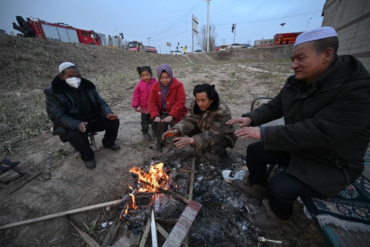 Orang-orang berkumpul di samping api setelah gempa bumi di Dahejia, Kabupaten Jishishan di provinsi Gansu, China pada 19 Desember 2023. Gempa China tersebut dilaporkan telah menewaskan 127 orang.