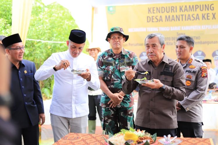 Bupati Kepulauan Meranti Muhammad Adil (kiri) makan nasi tumpeng bersama Gubernur Riau Syamsuar pada acara syukuran Desa Mantiasa, Kecamatan Tebing Tinggi Barat, Kabupaten Kepulauan Meranti, Riau, Kamis (26/1/2023).