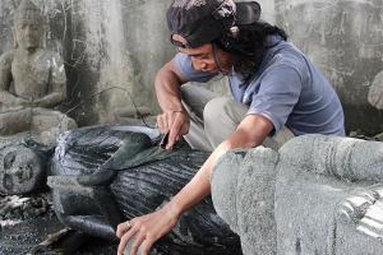 Lola (35), salah seorang pematung di Desa Wates Umpak, Trowulan, Mojokerto, Jawa Timur, sedang memahat patung Siwa berdiri, Rabu (11/12/2013).