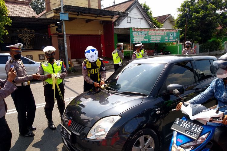 Petugas kepolisian dari Satlantas Polres Blitar memasang pita janur kuning pada kendaraan pemudik yang melakukan pelanggaran di Jalan Kusumabangsa, Kanigoro, Kabupaten Blitar, Minggu (24/4/2022)