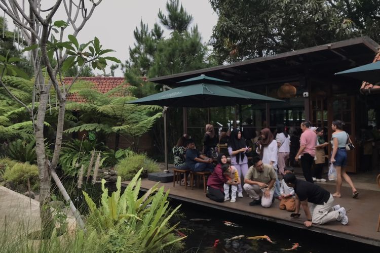 Wisatawan sedang berada di pinggir kolam ikan di Hutanika, Bandung, Jawa Barat pada Minggu (29/6/2025).