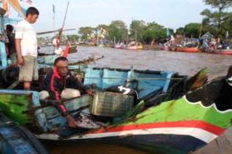 Seorang nelayan Desa Gempolsewu, Rowosari, Kendal, Jawa Tengah, tengah membereskan perlengkapan perahunya yang rusak akibat diterjang banjir bandang luapan Kali Kuto, Minggu (14/7/2013) dinihari.