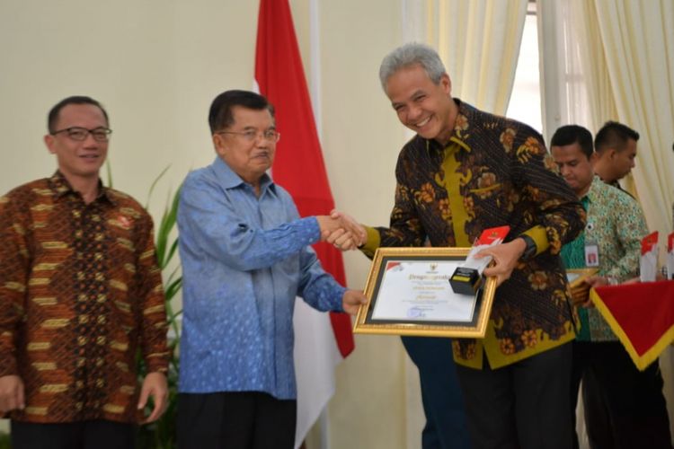 Wakil Presiden RI Jusuf Kalla memberikan penghargaan kepada Gubernur Jawa Tengah Ganjar Pranowo pada Penganugerahan Keterbukaan Informasi Badan Publik, di Istana Wakil Presiden, Jakarta, Senin (5/11/2018).