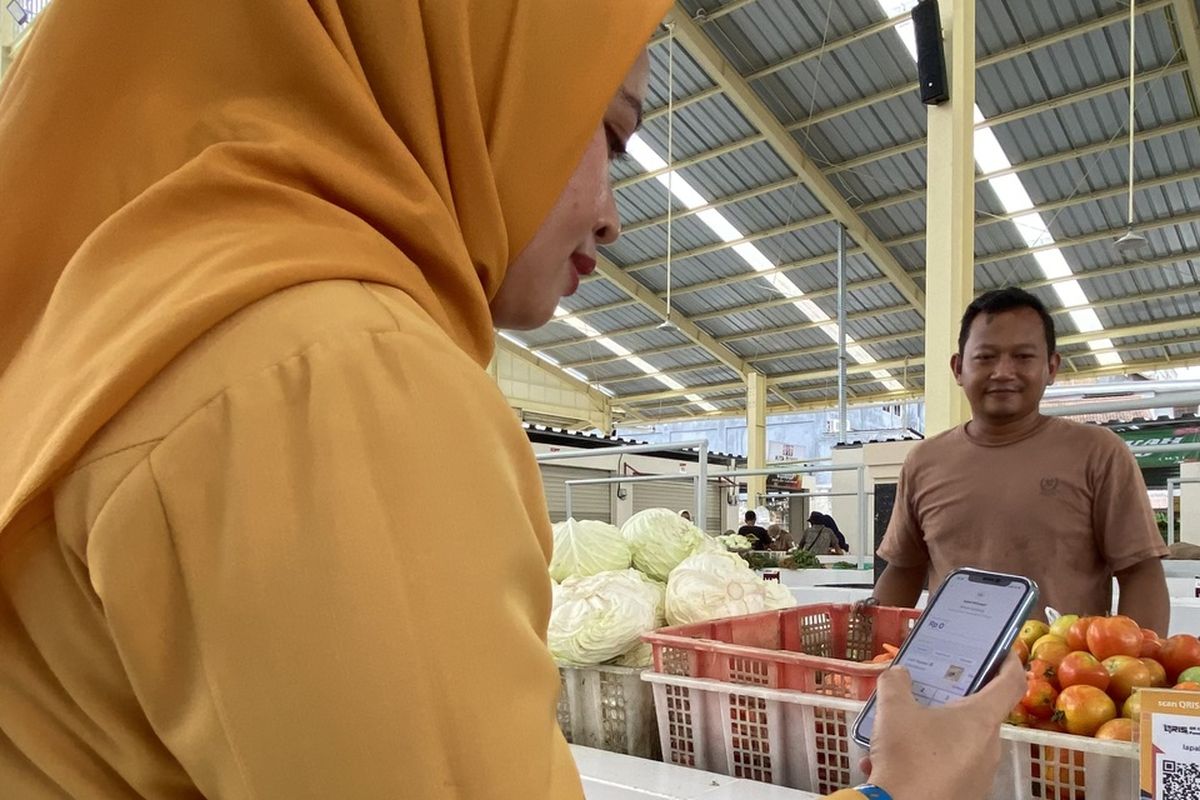 Salah seorang pembeli melakukan pembayaran menggunakan QRIS di pedagang sayur di Pasar Raya Lebak Budi, Kota Bandar Lampung, Senin (29/4/2024) siang.