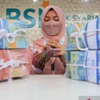 Karyawan Bank Syariah Indonesia sedang menghitung uang.