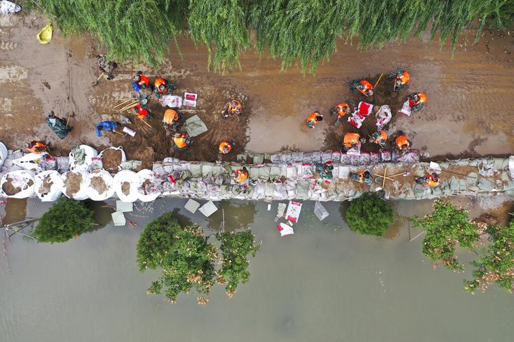 Dalam foto yang dirilis oleh Xinhua News Agency ini, foto udara menunjukkan tim penyelamat membentengi tanggul sementara terhadap banjir di Desa Lianbo di Kota Hejin, di Provinsi Shanxi, China utara, Minggu, 10 Oktober 2021.