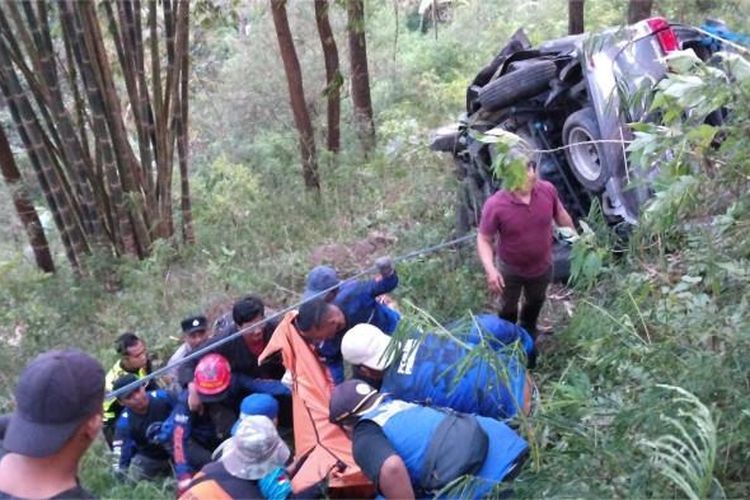 REM BLONG - Polisi bersama potensi relawan dan warga setempat saat mengevakuasi korban meninggal, dari dalam mobil Innova yang mengalami rem blong terjun ke jurang jalur Cangar-Pacet, Minggu (5/10/2025).  Seluruh korban dievakuasi ke Rumah Sakit Sumber Glagah, Pacet  