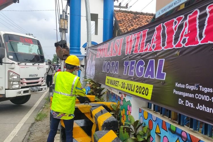 Seorang pekerja tengah menyiapkan beton MCB untuk menutup jalan perbatasan Kota/Kabupten Tegal, Minggu (29/3/2020), sebagai upaya Pemkot Tegal mengisolasi wilayah setelah ditemukan satu warganya yang positif corona. 